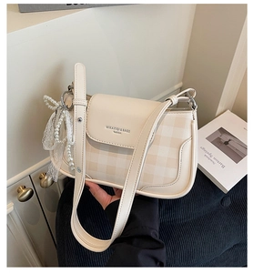 Nahaufnahme der cremefarbenen Punkte-Tasche mit Perlenspitzen-Anhänger und Markendetail