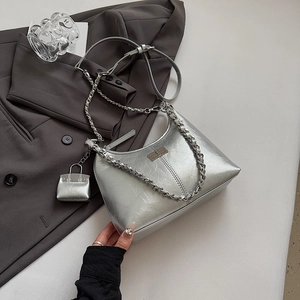 Détail du sac à main argenté plissé avec chaîne en métal et pendentif créatif de mini sac