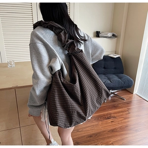 Detailed view of brown checkered crossbody bag with stylish pleated wide shoulder strap