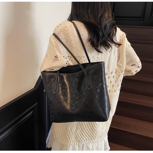 Vue détaillée du grand sac cabas noir à motifs géométriques porté à l'épaule par le mannequin