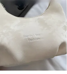 Close-up of cream white crescent bag showing premium leather texture and embossed logo