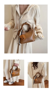 Detailansicht der braunen Leder-Eimertasche mit Ringgriff und Teddybär-Anhänger Accessoire