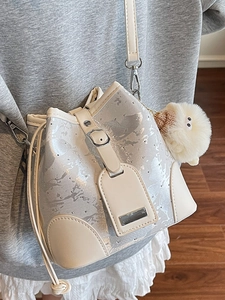 Chic women's bucket bag in champagne metallic finish with rivets and plush charm decoration
