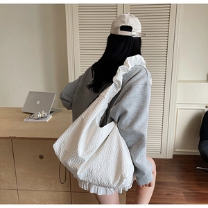 Detailed close-up of white bubble texture tote bag with ruffled edges in a cozy room