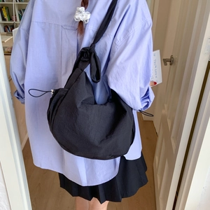Minimalist black crescent crossbody bag with knotted strap and drawstring details