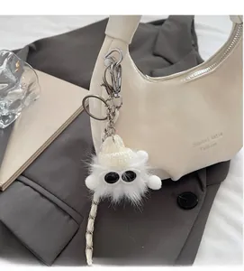 Detail of white plush cloud bag charm with knit hat on a premium white leather shoulder bag