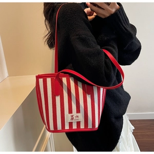 Detail of red and white striped canvas tote bag featuring vibrant red shoulder straps