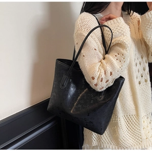 Gros plan d'un sac cabas noir avec texture gaufrée de chiffres et lettres sur la sangle
