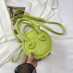 Close-up of bright green round mini bag featuring pebble leather texture and metal studs