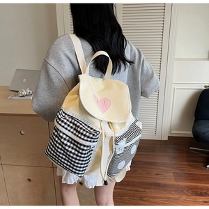 Detail view of canvas backpack featuring heart embroidery and blue plaid pocket patterns