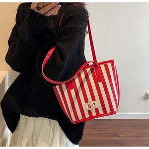 Detail of red and white striped canvas tote bag showing IXAO logo and leather trim