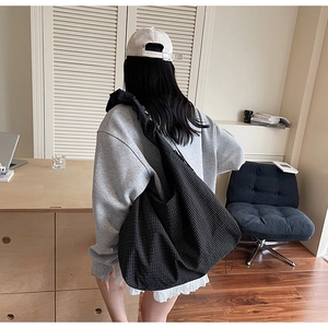 Rear view of a person wearing a large black and white checkered hobo bag with ruffled strap