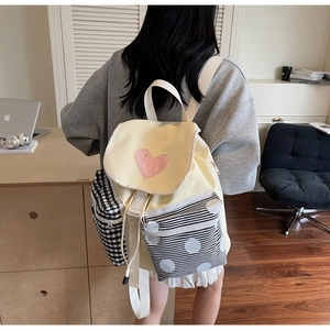 Close-up of the pastel yellow canvas backpack with pink heart patch and patterned pockets