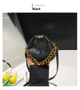 Détail du sac croissant en cuir grainé noir avec chaîne dorée et boucle métallique