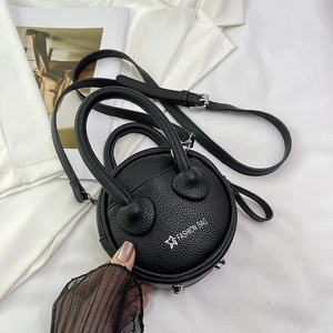 Detailed view of black round leather bag featuring silver metal feet and fashion logo
