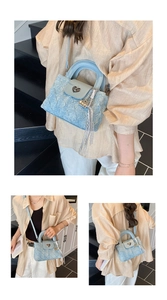 Detail of light blue denim style handbag with heart metal lock and tassel decoration