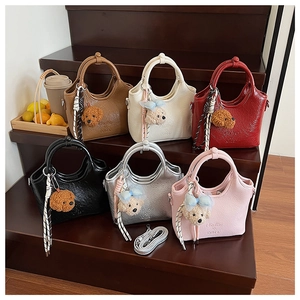 Detailansicht sechs farbiger Mini-Eimertaschen mit Plüsch-Anhängern und Bändern