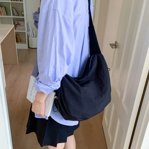 Detailed view of black nylon dumpling bag featuring side drawstring and zipper closure