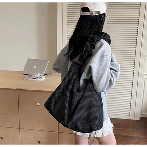 Detail of black checkered tote bag with stylish ruched shoulder strap for daily commuting