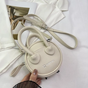 Macro detail of beige round bag with lychee texture and metallic bottom rivets