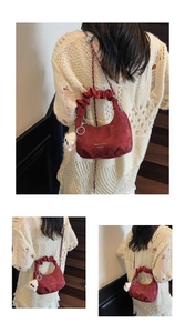 Detail view of burgundy crescent bag with pleated handle, chain strap and plush pendant