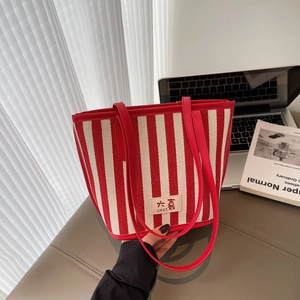 Close-up of red and white striped canvas tote bag with DAXI leather brand tag