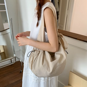 Detail view of large apricot shoulder bag featuring a stylish decorative bow and drawstring