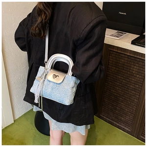 Detail of light blue pleated handbag with silver handle, lace ribbon and heart lock