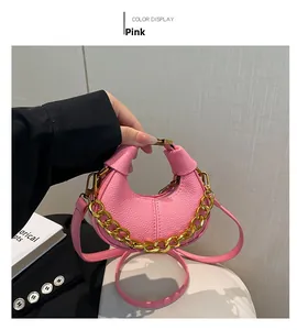 Détail du sac demi-lune rose avec texture grainée, chaîne dorée et fermoir métal
