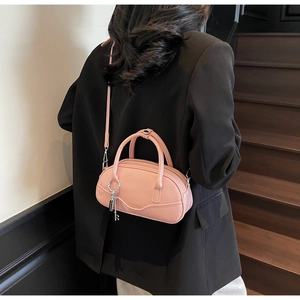 Pink vintage bowling bag with crossbody strap and key charm on a black blazer