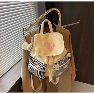 Detail of color-block backpack showing heart patch and side pockets with pattern contrast