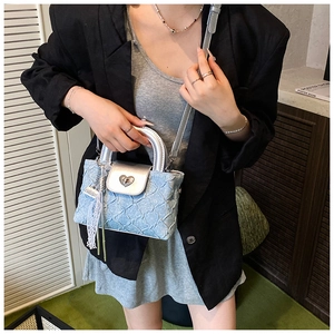 Close-up of light blue pleated handbag with silver heart lock and lace floral charm