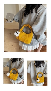 Detail of yellow crescent cloud bag with pleated handle and white monster plush charm
