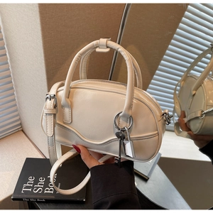 Detailed macro view of cream bowling bag with glossy leather and silver padlock accessory