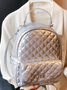 Silver quilted mini backpack with rhinestone decor and metal lock held by a person