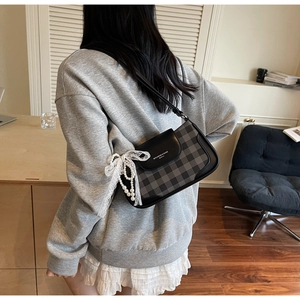 Detailaufnahme der Retro-Karotasche mit weißer Spitzenschleife und Perlenanhänger