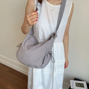 Detail of grey nylon crossbody dumpling bag featuring drawstring closure and wide strap