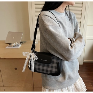 Detailansicht der karierten Schultertasche mit Spitzenschleife und elegantem Perlenanhänger