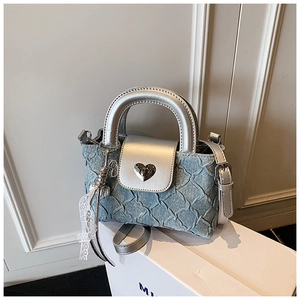 Detail of light blue quilted denim handbag with silver mirror trim and heart metal clasp