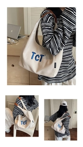 Detail of canvas tote bag with blue TCT embroidery and brown leather handles