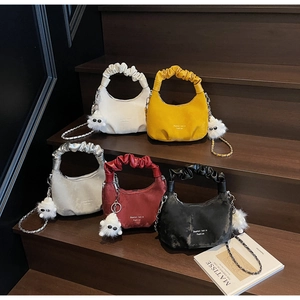 Detail showing colorful pleated cloud bags with scrunchie handles and plush charms on stairs