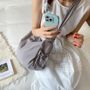 Detail of grey nylon crescent crossbody bag with drawstring design and metal hardware