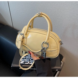 Detail of a creamy yellow bowling handbag with matte leather texture and silver hardware