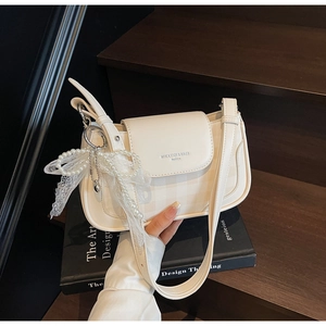 Detailansicht der cremefarbenen Kunstledertasche mit Perlen-Spitzenschleife und Logo