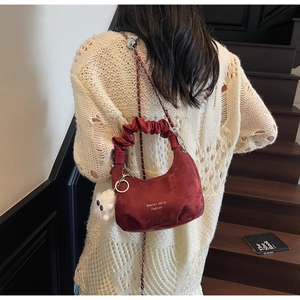 Detail of dark red ruched cloud bag with shoulder strap and plush monster charm