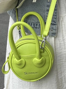 Neon green round mini crossbody bag with litchi texture shown on female model
