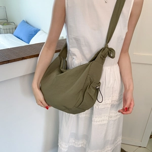 Detail of army green nylon dumpling bag with adjustable knotted shoulder strap and zipper