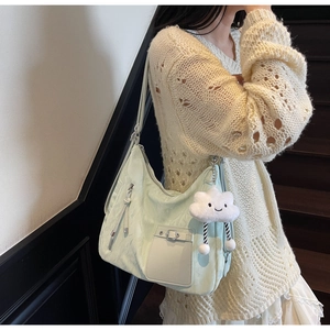 Detail view of mint green hobo bag with cloud charm on model over cream knit outfit