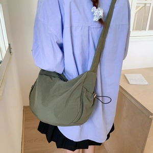 Detail of army green nylon dumpling bag showing side drawstring and wide strap