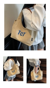 Detail of beige canvas tote with blue TCT embroidery and brown leather handle
